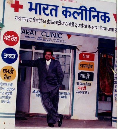 The Bharat Clinic storefront, with a man in a suit standing in the open doorway beneath a painted signboard.